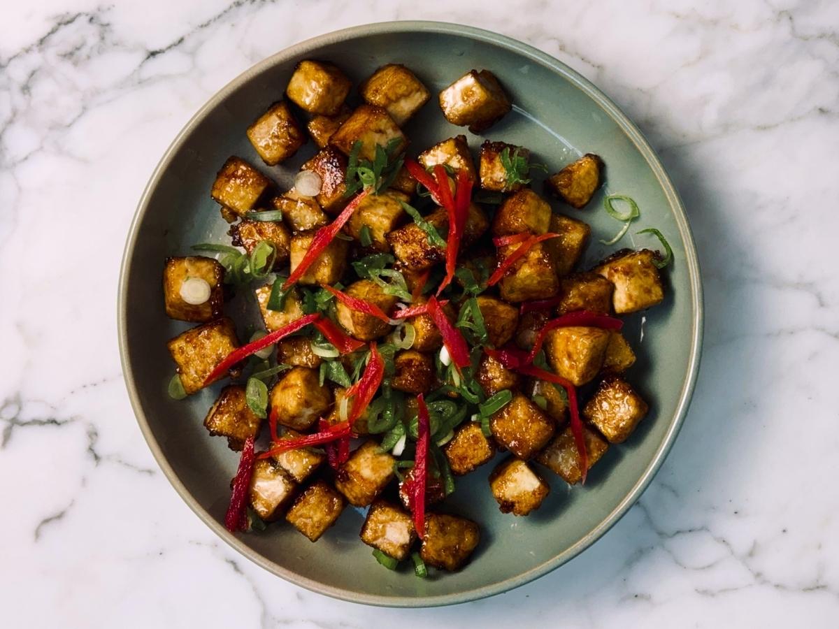 finished sticky tofu on a serving dish garnished with pickled ginger and green onions