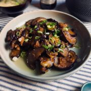 Beer and eggplant stir-fry in a shallow bowl garnished with spring onions