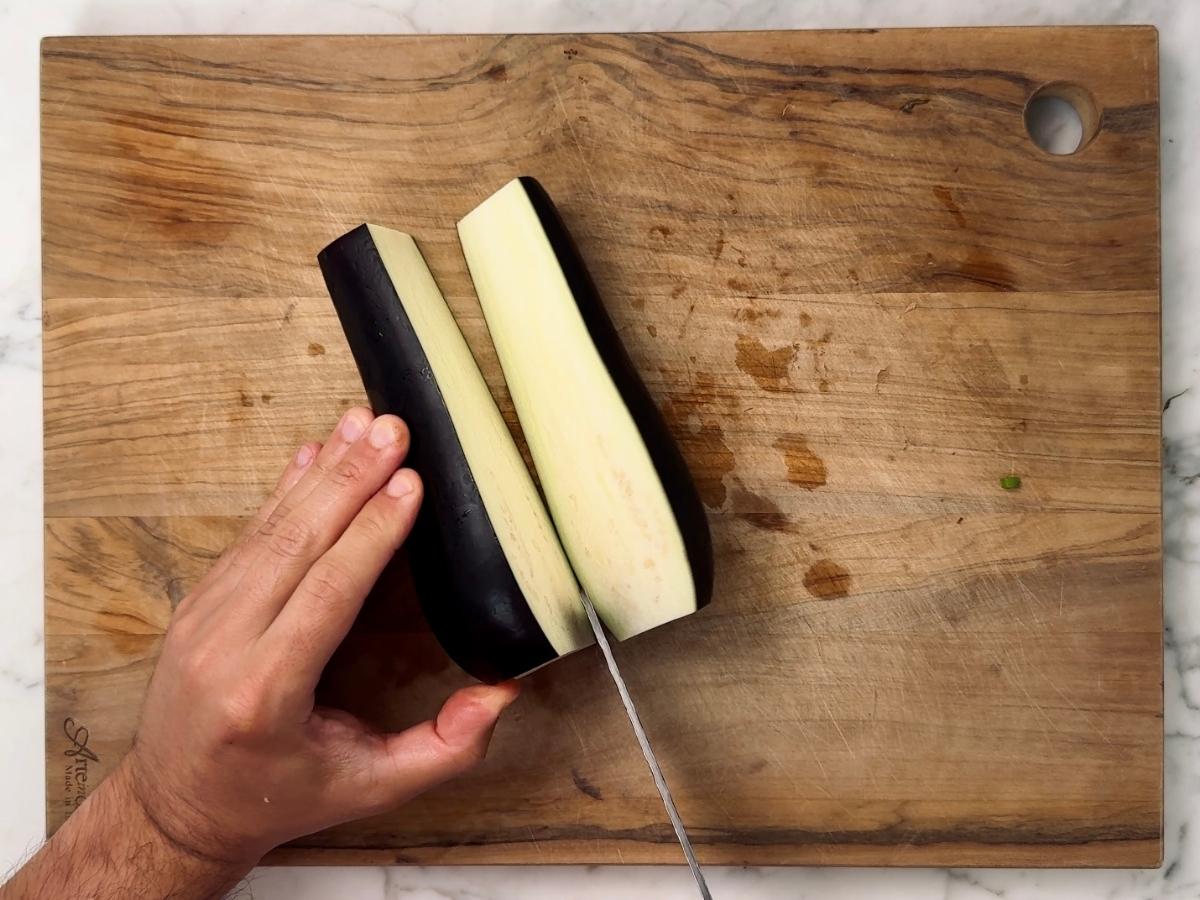 trimmed eggplant being halved