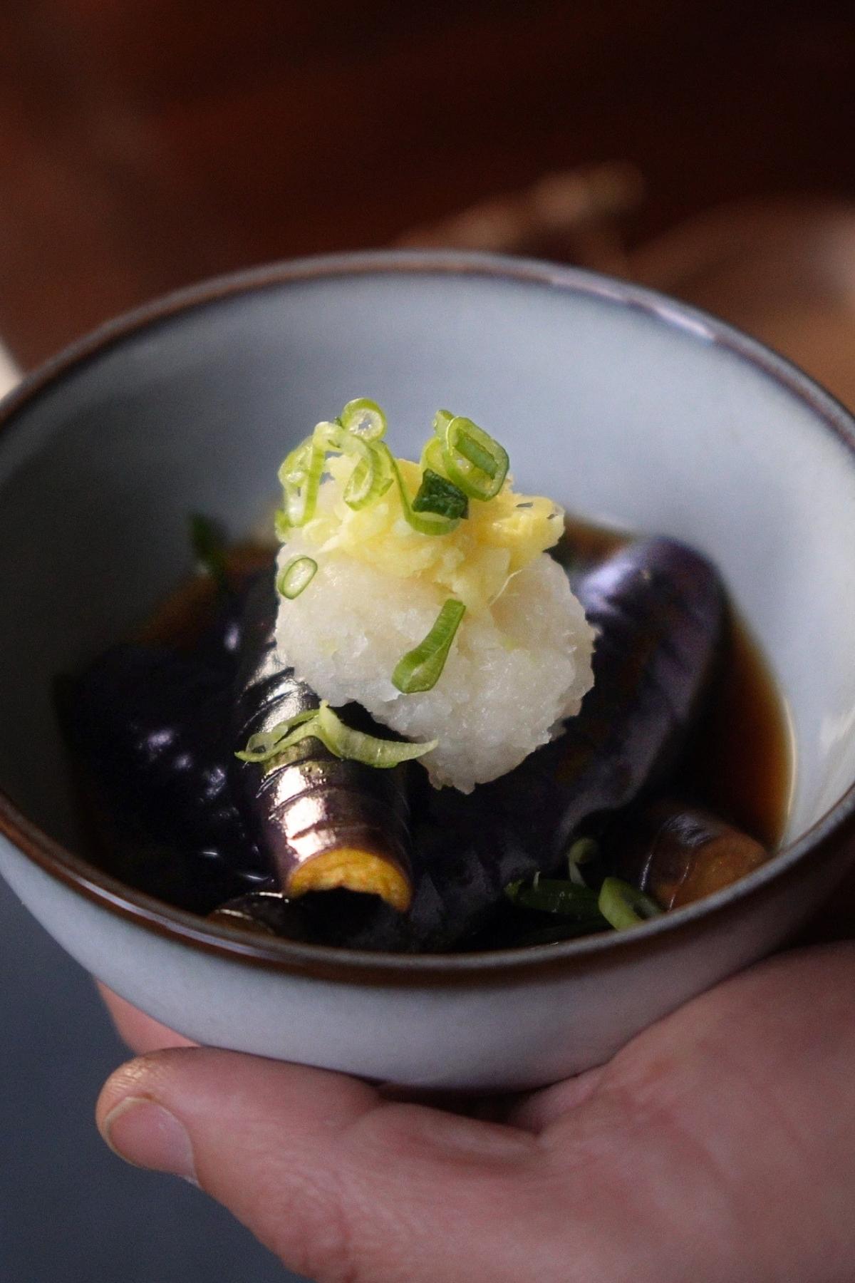 Eggplant agebitashi in a bowl garnished with grated daikon, spring onions and ginger