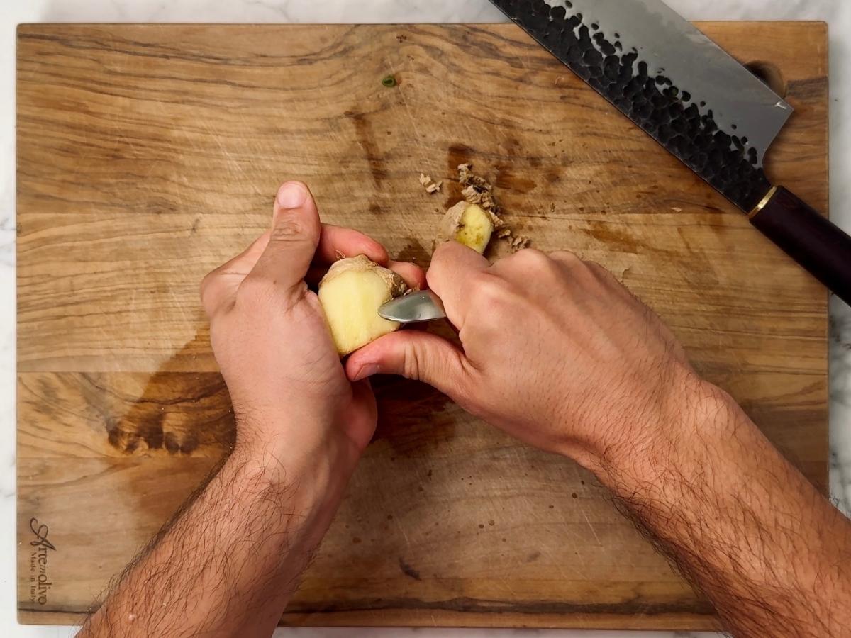 ginger being peeled with a teaspoon