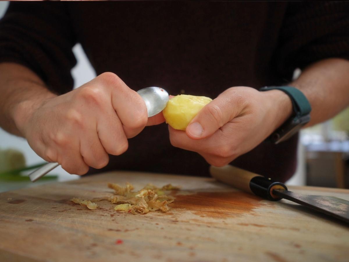 ginger being peeled using teaspoon