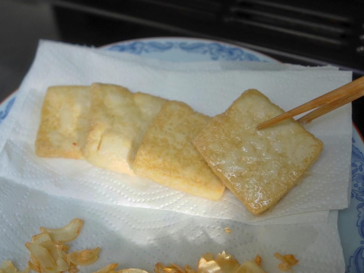 fried tofu being placed on a paper towelled plate