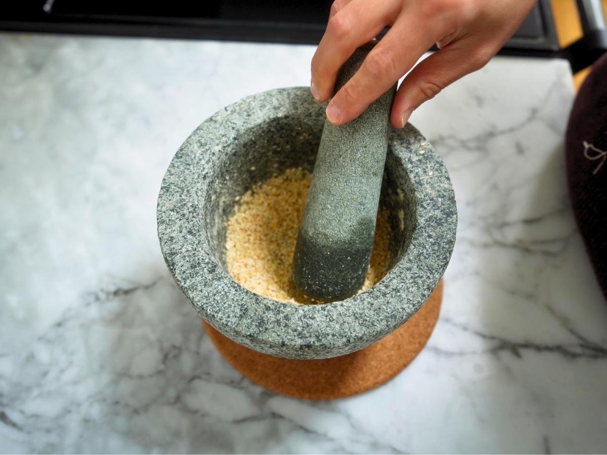 toasted sesame seeds being ground in a pestle and mortar