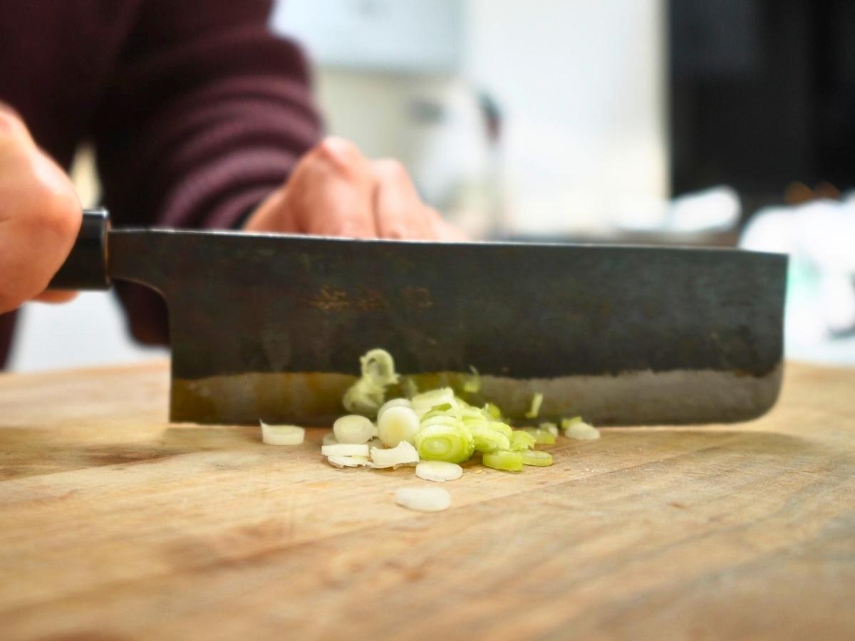 green onions being sliced into thin discs
