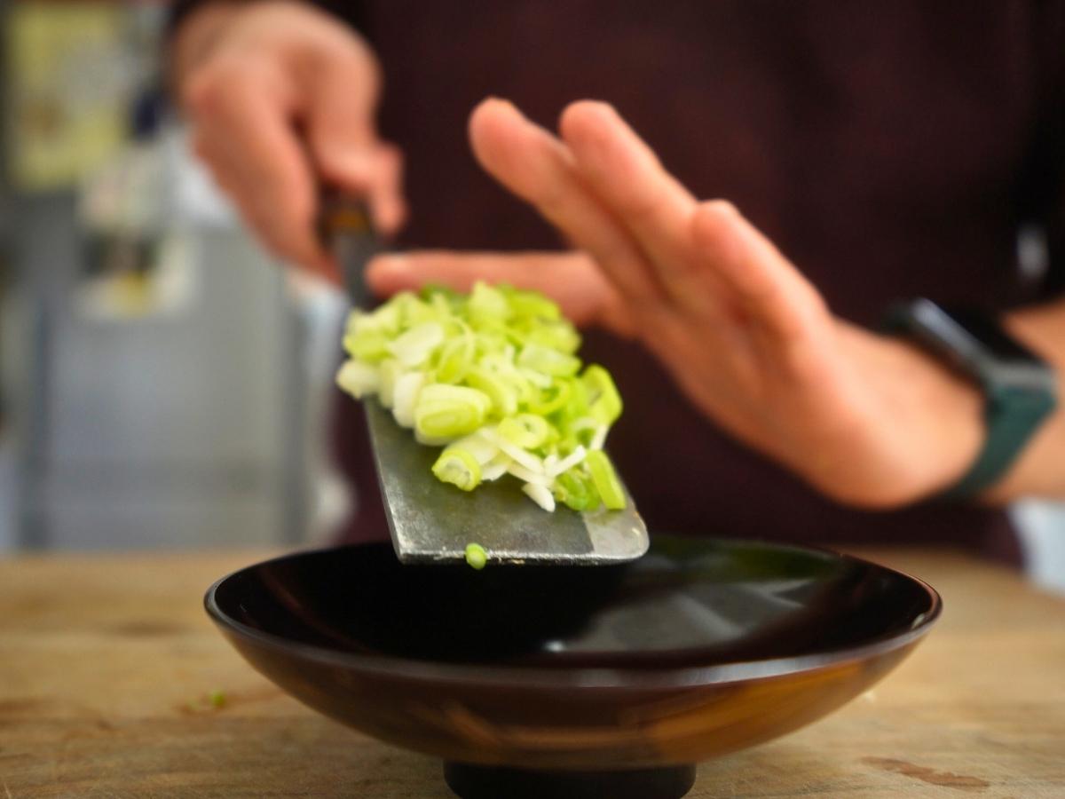 sliced green onion being set aside in a small bowl