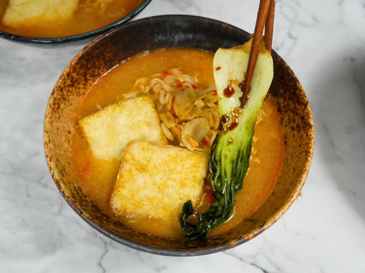 toppings being placed on ramen and broth