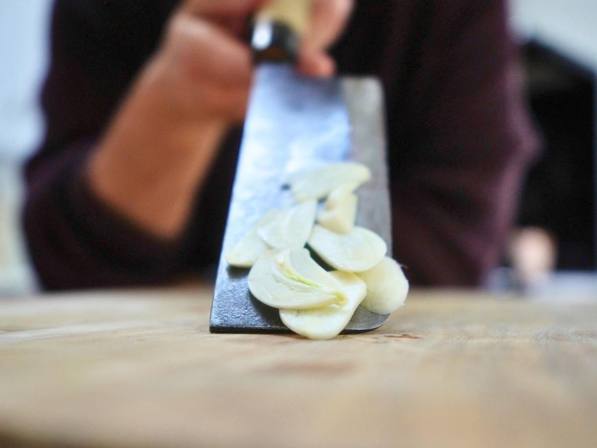 thinly sliced garlic on a knife being shown up close