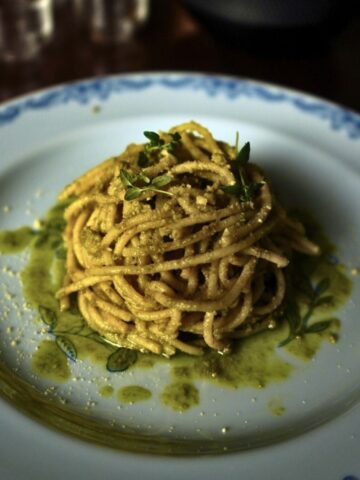 miso walnut pesto spaghetti on a large ound plate. Garnished with thyme