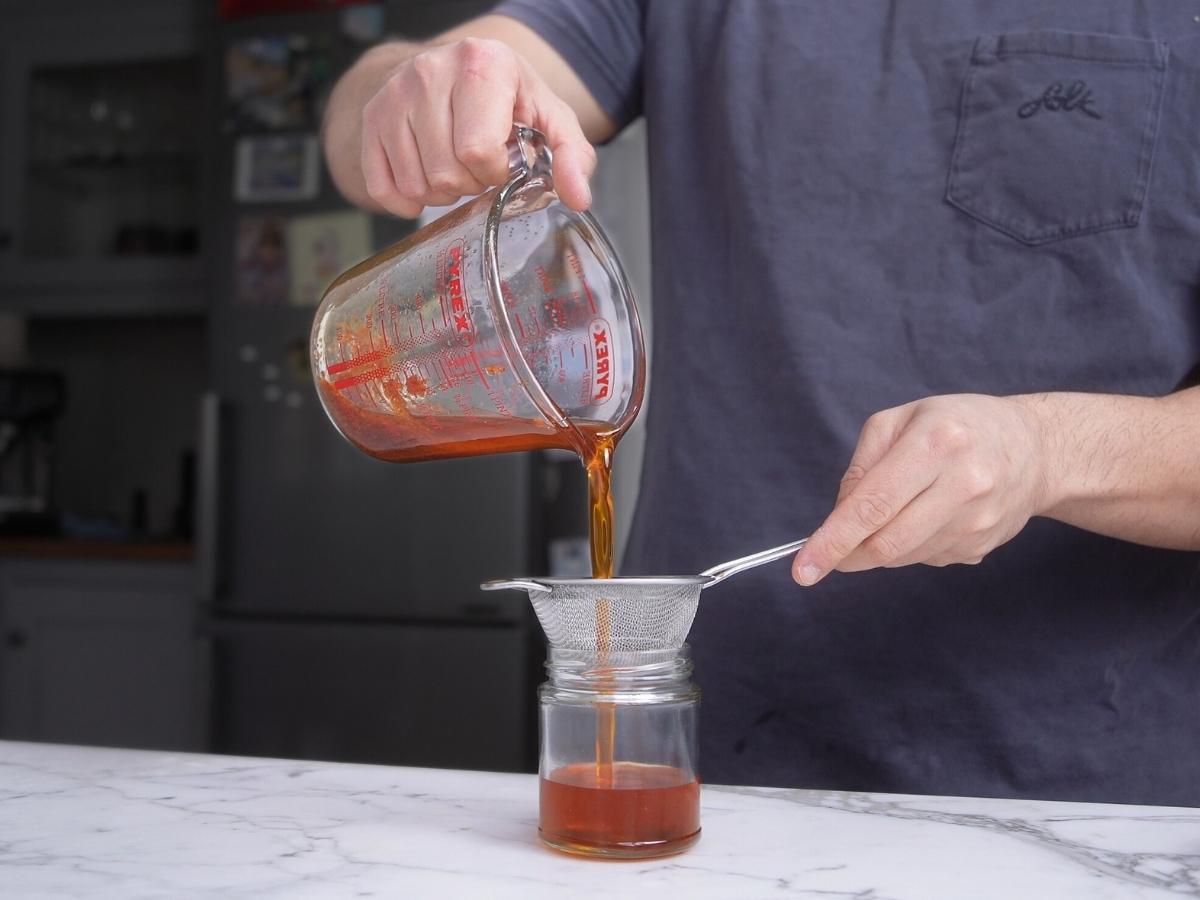 pouring homemade rayu chili oil into glass jar