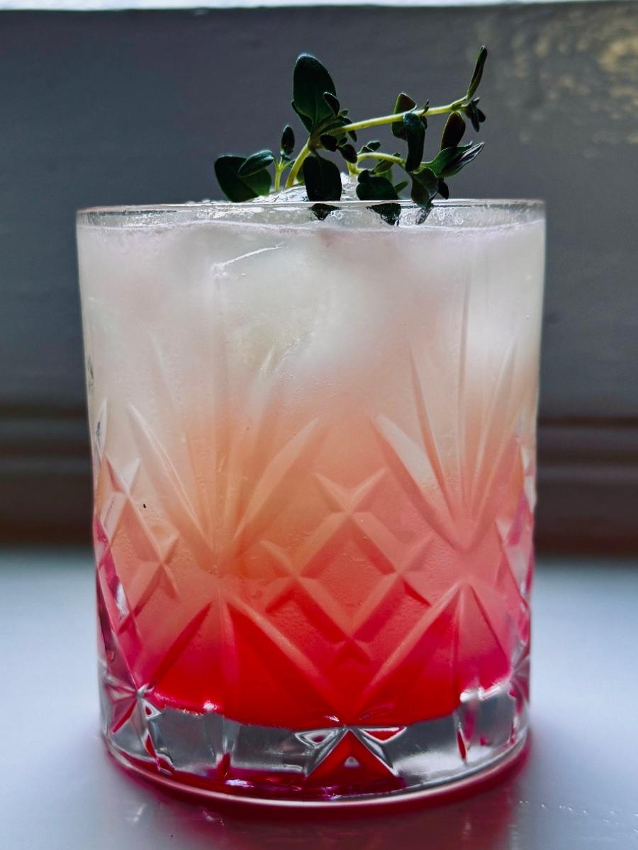 close up of yuzu fizz cocktail garnish with fresh thyme